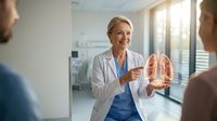 Female doctor explaining lung anatomy to patients using medical model in modern hospital consultation room for healthcare education.