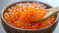 Fresh red caviar in ceramic bowl with wooden spoon, bright orange salmon roe close up view. Luxury seafood delicacy for gourmet appetizer and festive dining.