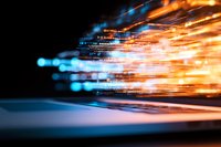 Abstract digital light trails in orange and blue colors against dark background create dynamic motion effect for technology and data transfer concepts.