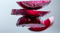Fresh red onion slices with water droplets stacked on white background. Organic vegetable ingredient for cooking and healthy nutrition recipes.