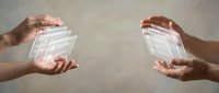 Two hands exchanging transparent digital currency or data blocks, representing financial transaction, digital payment, cryptocurrency transfer, or secure information exchange between parties.