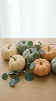 Autumn pumpkins in pastel colors arranged on wooden table with eucalyptus branches for seasonal home decor and fall harvest celebration.
