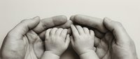 Adult hands gently protecting tiny baby feet in tender embrace symbolizing care, love, family bonds, parenthood, newborn safety and nurturing protection.