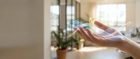 Female hands holding glowing digital icons representing modern technology and connectivity in bright home interior for business presentations.
