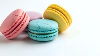 Colorful French macarons in pink, turquoise and yellow arranged on white background. Sweet pastry dessert cookies for bakery menu and confectionery design.