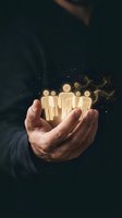 Male hand holding glowing team of people icons with magical particles on dark background. Concept for business leadership, teamwork, human resources, community support and employee engagement.