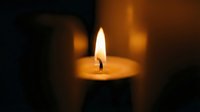 Warm glowing candle flame creates peaceful ambiance with soft golden light against dark background for meditation and relaxation atmosphere.