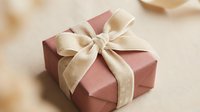 Pink gift box with elegant beige velvet ribbon bow on neutral background, perfect for holiday, wedding, or birthday celebration concepts.