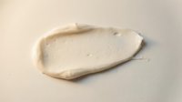 Creamy white cosmetic product smear on neutral background showing smooth texture and consistency for skincare and beauty applications.