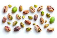 Raw and roasted pistachio nuts scattered on white background, whole and halved showing green kernels inside shells, fresh natural healthy snack pattern.