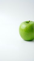 Fresh green apple with water droplets on clean white background with copy space for healthy eating and nutrition concepts.