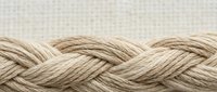Natural hemp rope with twisted braided texture on neutral background for nautical and craft projects.