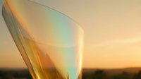Large soap bubble with rainbow iridescent colors floating against warm sunset sky background creating dreamy atmospheric scene.