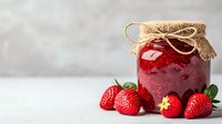 Fresh strawberry jam in glass jar with burlap lid, surrounded by ripe whole strawberries on light background, rustic food styling for packaging design.