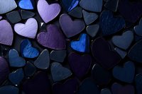 Dark moody background with purple and blue heart shapes arranged in pattern, dramatic lighting creates depth and texture on metallic surface. Romantic design element.
