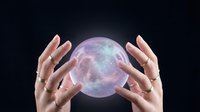 Female hands holding glowing mystical crystal ball with cosmic energy and starlight effects on dark background for fortune telling and spiritual guidance.