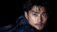 Young Asian man with wet hair and intense gaze wearing dark hoodie against black background for dramatic portrait photography and commercial use.