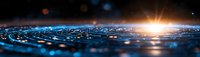 Dramatic panoramic sunrise over textured blue surface with water droplets and lens flare creating futuristic horizon line against dark background.