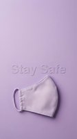 Purple fabric face mask on a matching lavender background with Stay Safe text, copy space for health and safety campaigns.