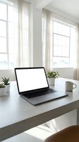 Modern laptop with blank white screen on minimalist desk workspace with plants and coffee mug in bright natural light office setting for remote work and productivity.