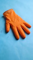 Single orange latex protective glove displayed on bright blue background, suitable for healthcare, safety, cleaning, and medical industry applications.