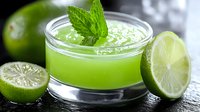 Fresh green smoothie with mint garnish and lime slices on dark wooden surface. Healthy detox drink for wellness lifestyle and nutrition concepts.