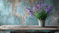 Beautiful purple wildflowers in ceramic pot on rustic wooden table against textured turquoise wall, perfect for interior design, home decor, or garden inspiration.