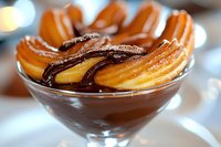 Fresh churros arranged in glass bowl with dark chocolate dipping sauce, close-up view showing crispy golden pastry texture and rich melted chocolate.