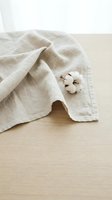 Natural linen fabric with cotton flower on wooden surface showcasing organic textile materials and sustainable fashion concepts for eco-friendly design projects.