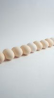 Row of natural wooden beads arranged in line on white background for crafting jewelry making and DIY projects.