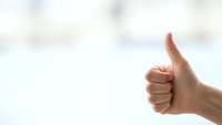Hand showing thumbs up gesture against soft blurred background expressing approval, success and positive feedback for business and communication concepts.