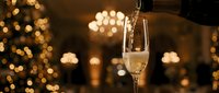Champagne pouring into glass with golden bokeh lights in background, celebration and festive occasion for holidays, parties, weddings, and toasts.