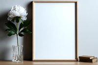Elegant wooden frame mockup with white peony in crystal vase and vintage book on wooden table against neutral wall background. Perfect for artwork display.