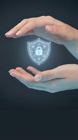 Protective hands surrounding glowing cybersecurity shield with padlock icon representing data protection and digital security solutions for business.