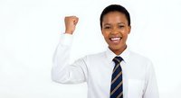 Young African American businessman in white shirt and striped tie celebrating success with raised fist gesture, smiling confidently on white background.