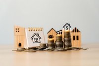 Real estate investment concept with wooden house models, stacked coins and dollar sign representing property finance and mortgage planning.