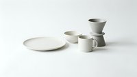 Minimalist white ceramic dinnerware set with plates, bowls and mugs arranged on clean background for modern kitchen and dining room decor.