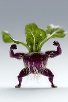 Purple radish root carved into muscular figure pose with green leaves on top, showing creative food art against light background. Roots visible as natural details.