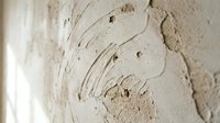 Textured white plaster wall with artistic swirl patterns and natural imperfections creating abstract relief surface for interior design backgrounds.