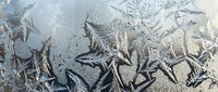 Intricate frost patterns create delicate crystalline formations on glass surface, showcasing nature's artistry in winter ice crystals and frozen textures.