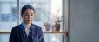 Professional businesswoman with closed eyes in modern office environment practicing mindfulness meditation during work break for stress relief and mental wellness.