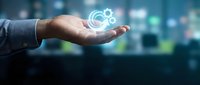 Businessman hand holding glowing gear icon with digital network connection on blurred city background, representing technology, innovation, and business solutions.