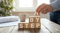 Business professional arranging wooden blocks spelling STEP BY STEP on office desk, representing strategic planning and methodical approach to success.