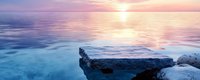 Tranquil seascape with rocky coastline at sunset, calm turquoise waters reflecting pink and purple sky, peaceful ocean horizon for meditation and relaxation.