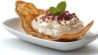 Crispy pastry shell filled with light whipped cream, topped with crumbled chocolate and fresh mint leaf garnish on white ceramic plate, food photography.