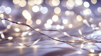 Glowing fairy lights creating magical bokeh effect on purple background, delicate wire string lights illuminate festive atmosphere for holiday decor.