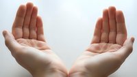 Open cupped hands gesture showing palms in protective or receiving position against white background for spiritual and wellness concepts.
