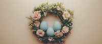 Pastel blue Easter eggs nestled in delicate wreath adorned with pink roses and fresh greenery against neutral beige background, spring holiday decor.