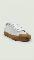 White low-top canvas sneaker with gum rubber sole and white laces on neutral background, casual streetwear footwear for fashion and retail use.