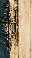 Rusty metal ladder rungs embedded in weathered concrete wall with peeling paint, showing industrial decay and abandonment for architectural and urban decay projects.